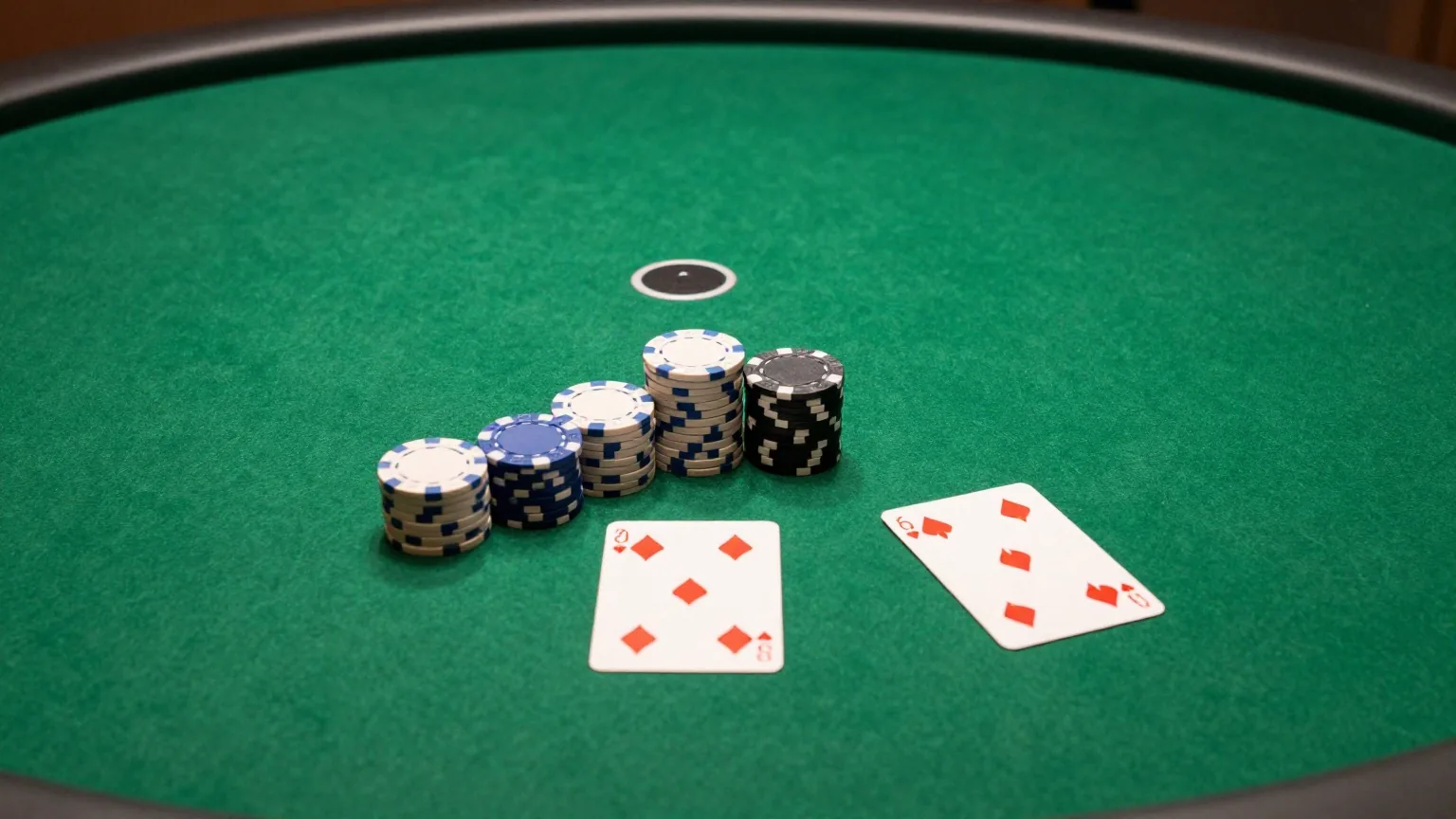 Grüner Filztisch von oben mit Dealer-Button, drei kleinen Chipstapeln und zwei verdeckten Spielkarten